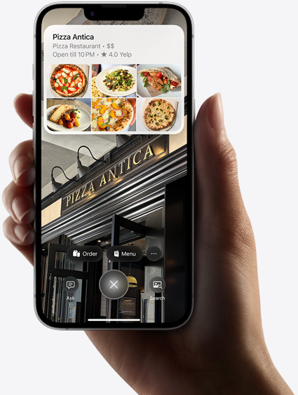 Ръка, която държи iPhone 16e, на който са показани резултати от търсене с помощта на визуална интелигентност.