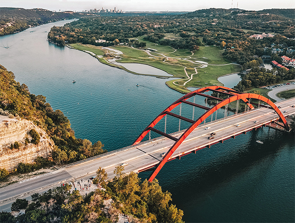 Aerial view of a river and a bridge in Austin, Texas, with the city in the background.