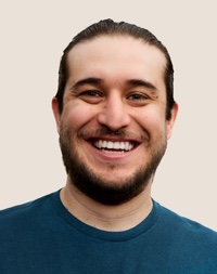 Portrait of a smiling Apple Retail team member with dark hair and a beard.
