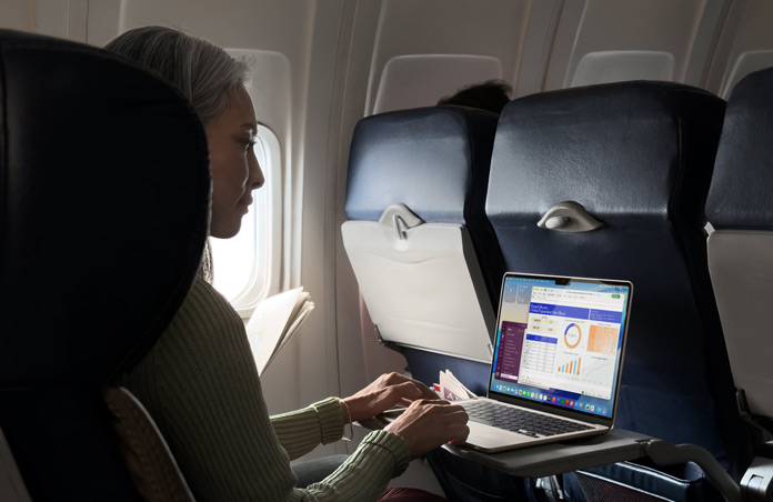 Eine Person, die in einem Flugzeug sitzt und auf dem MacBook Air arbeitet