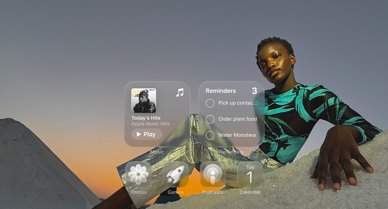 Wyświetlacz Liquid Glass z przejrzystymi ikonami aplikacji Apple Music, Przypomnienia, Zdjęcia, Gry, Podcasty i Kalendarz, które subtelnie rozmywają obraz tapety