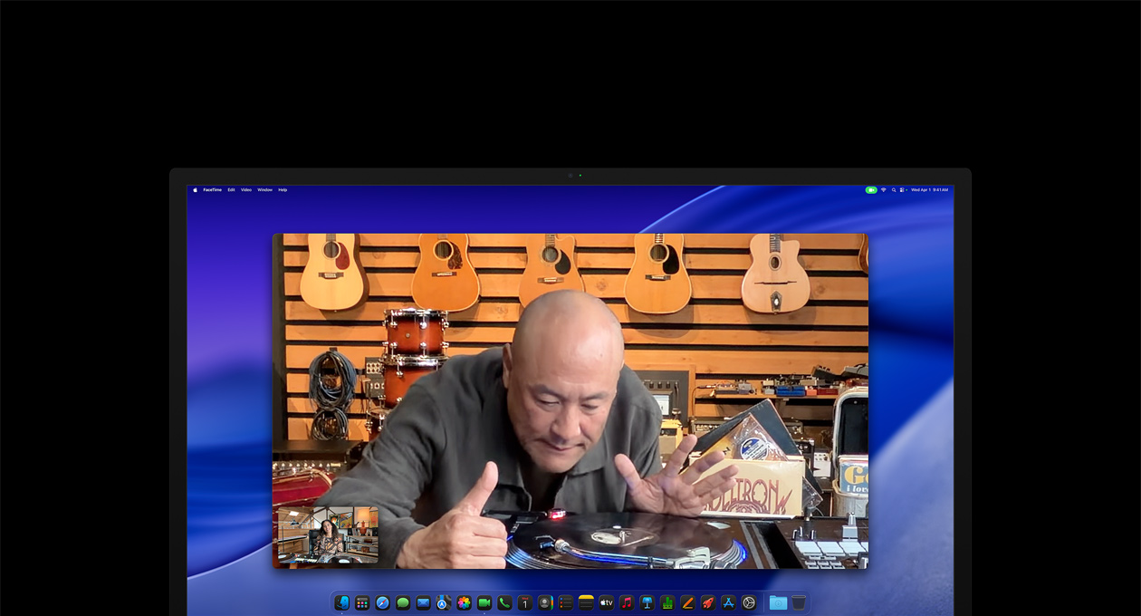 Podczas wideorozmowy osoba w sklepie z płytami przygląda się uważnie gramofonowi, pozostając w środku kadru dzięki kamerze Center Stage