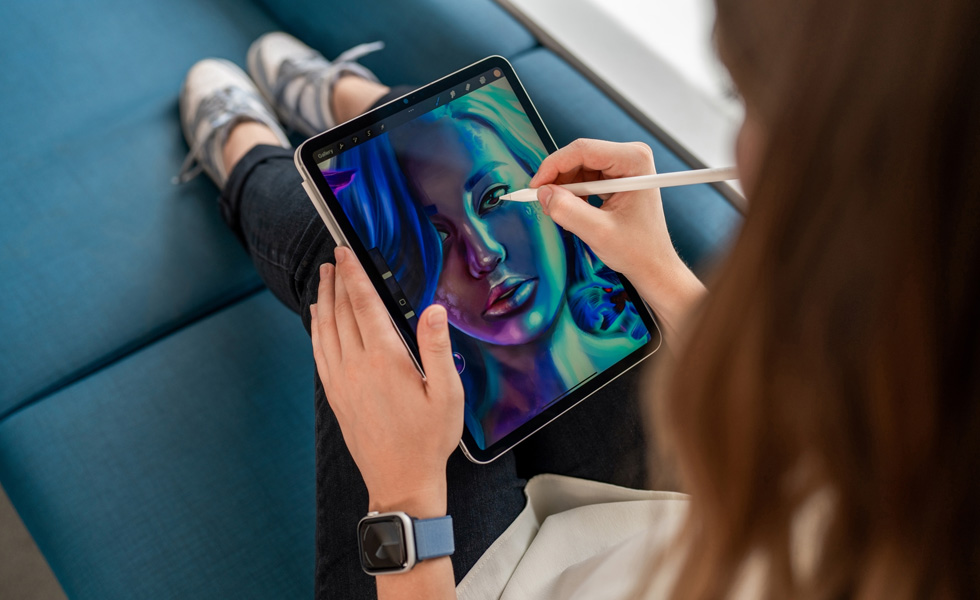 Seorang siswa memegang iPad di pangkuannya sambil menggambar di aplikasi Procreate menggunakan Apple Pencil