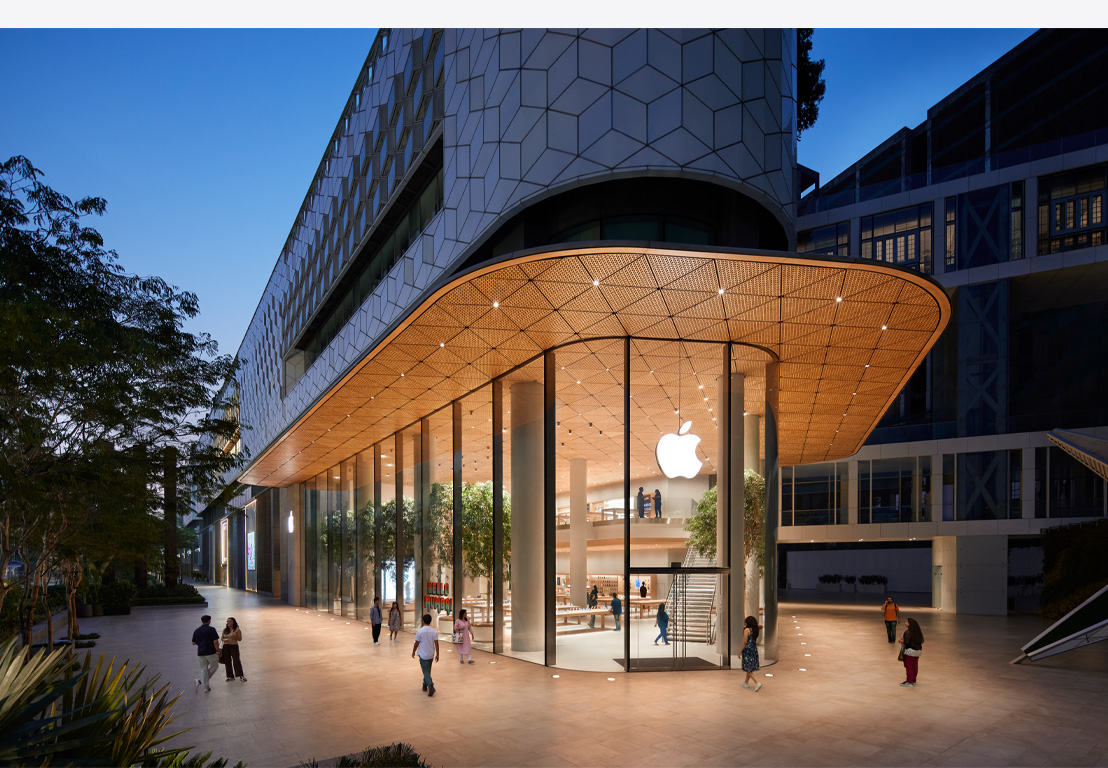 متجر Apple Store ليلاً، نوافذ زجاجية، مضاء من الداخل، شعار Apple في وسط الجزء العلوي من الباب الأمامي.